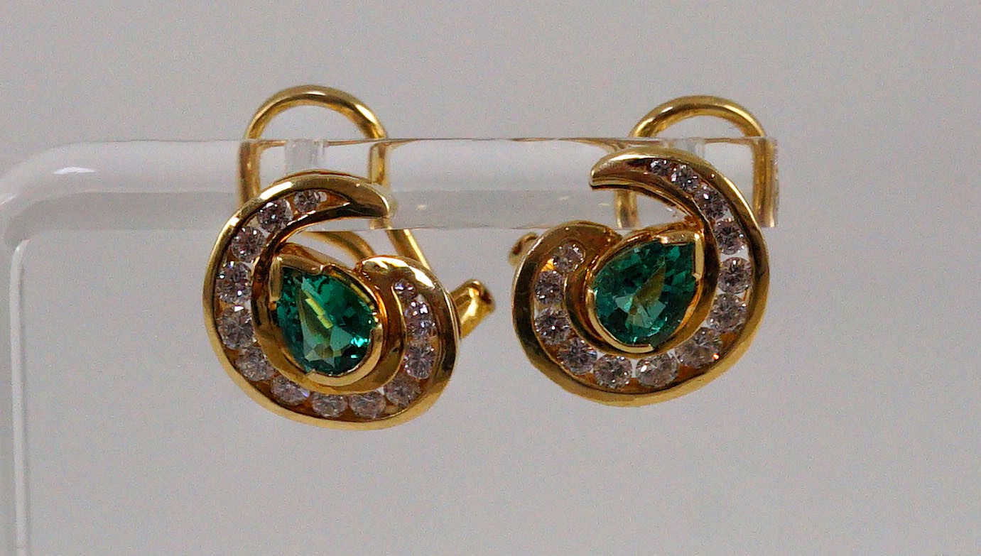 A modern pair of gold (tests as 18ct), emerald and diamond set scrolling cluster earrings